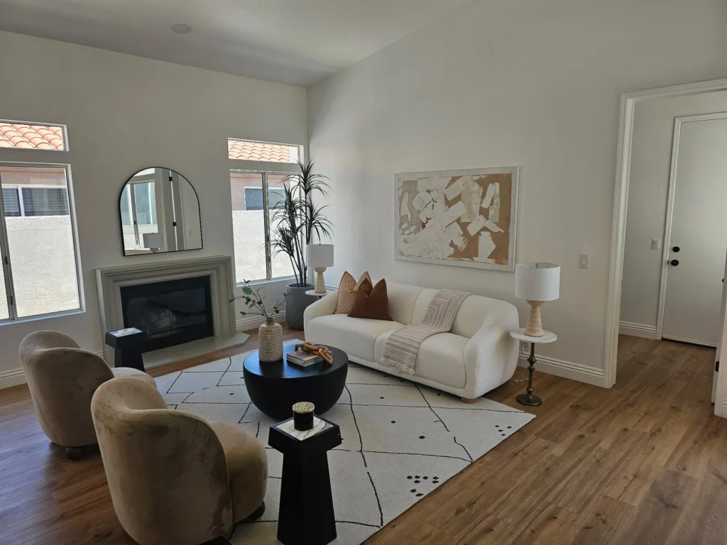 Bright living room with a fireplace, tall windows, wood flooring and a cream sofa.
